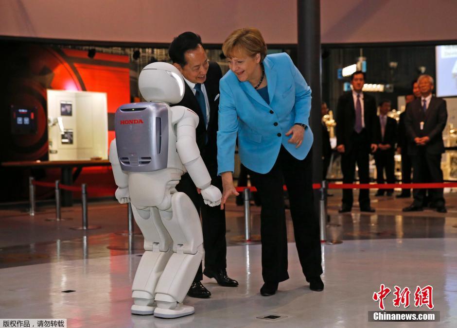 默克尔访问日本 与机器人握手互动
