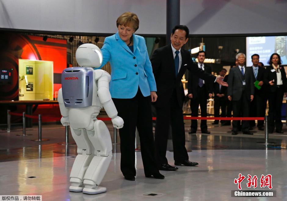 默克尔访问日本 与机器人握手互动