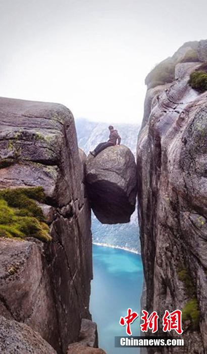 挪威游客冒雨登千米高悬石拍照