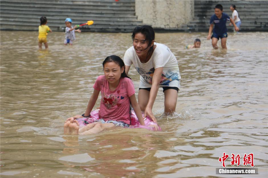 广西暴雨至柳江河水上涨 市民水中作乐