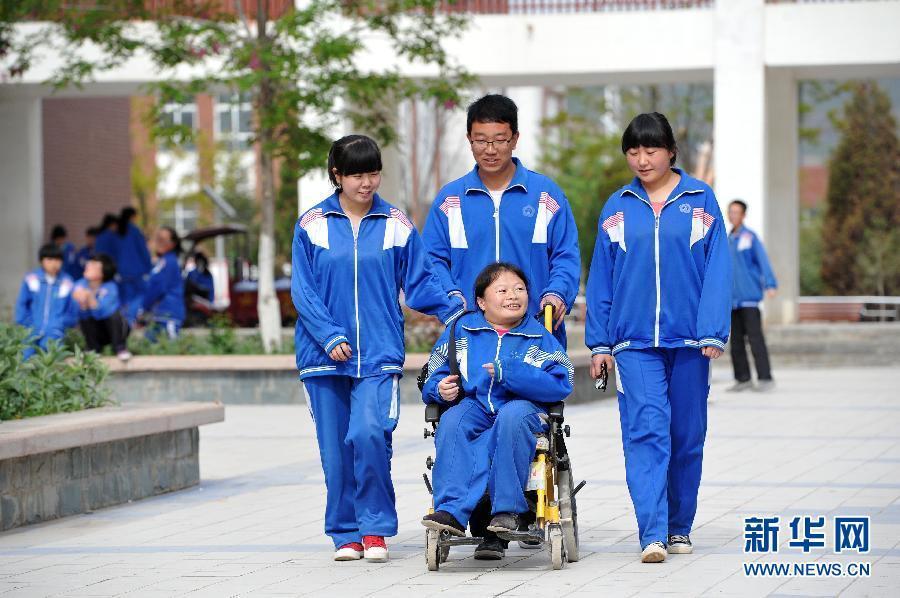 5月21日,在宁夏回族自治区西吉县西吉中学,同学们推着刘晓丽在校园里