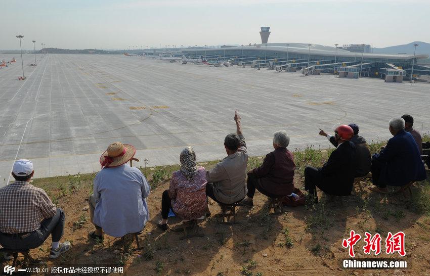山东蓬莱国际机场启用 村民集体坐山顶看飞机