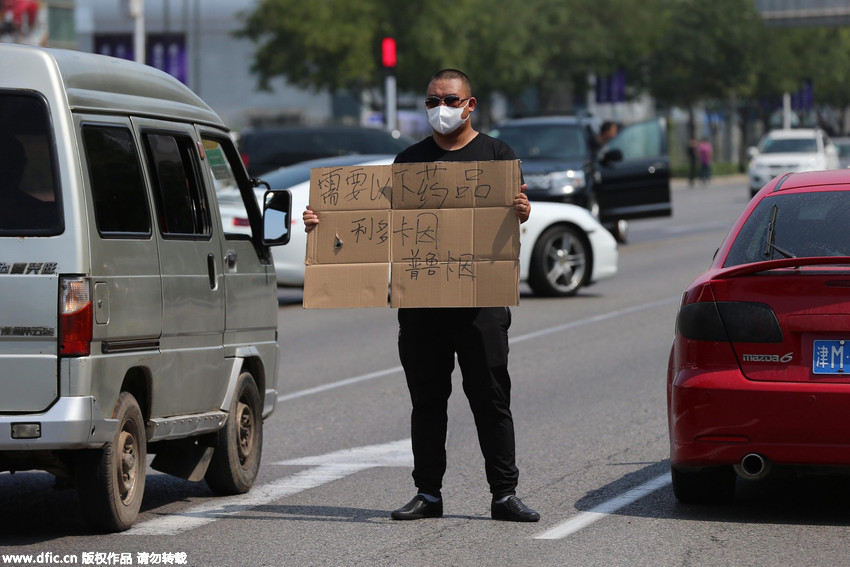 天津爆炸事故致物资药品短缺 志愿者烈日下举牌求帮助