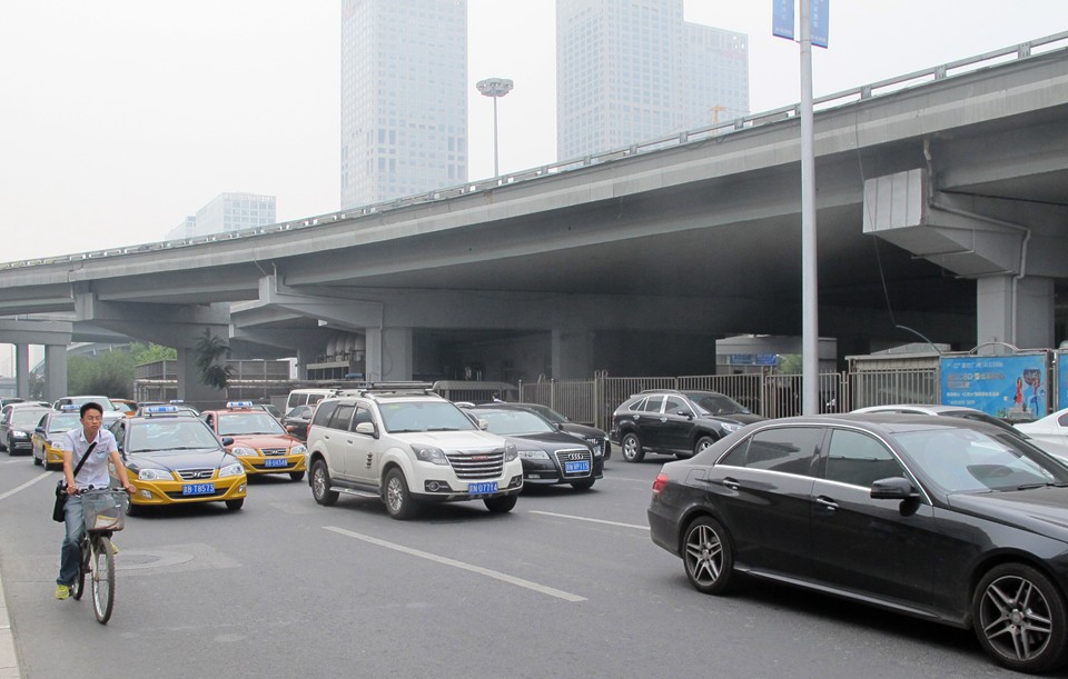 雾霾笼罩下的北京东三环国贸桥下的车流和骑自行车出行的市民.