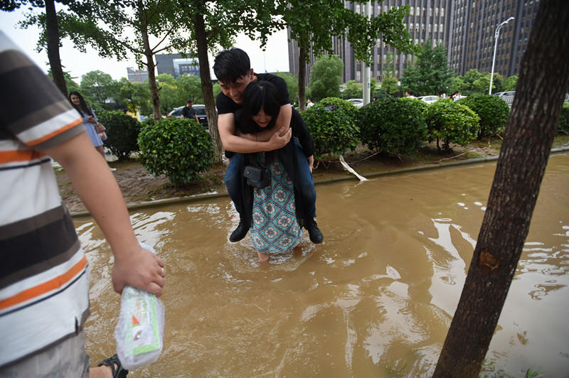 武汉一女孩不让男友湿鞋 直接背其淌水过马路