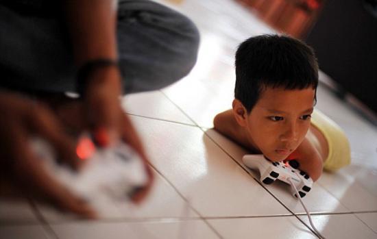 印尼11岁男孩天生无四肢 用下巴做功课打游戏(组图)