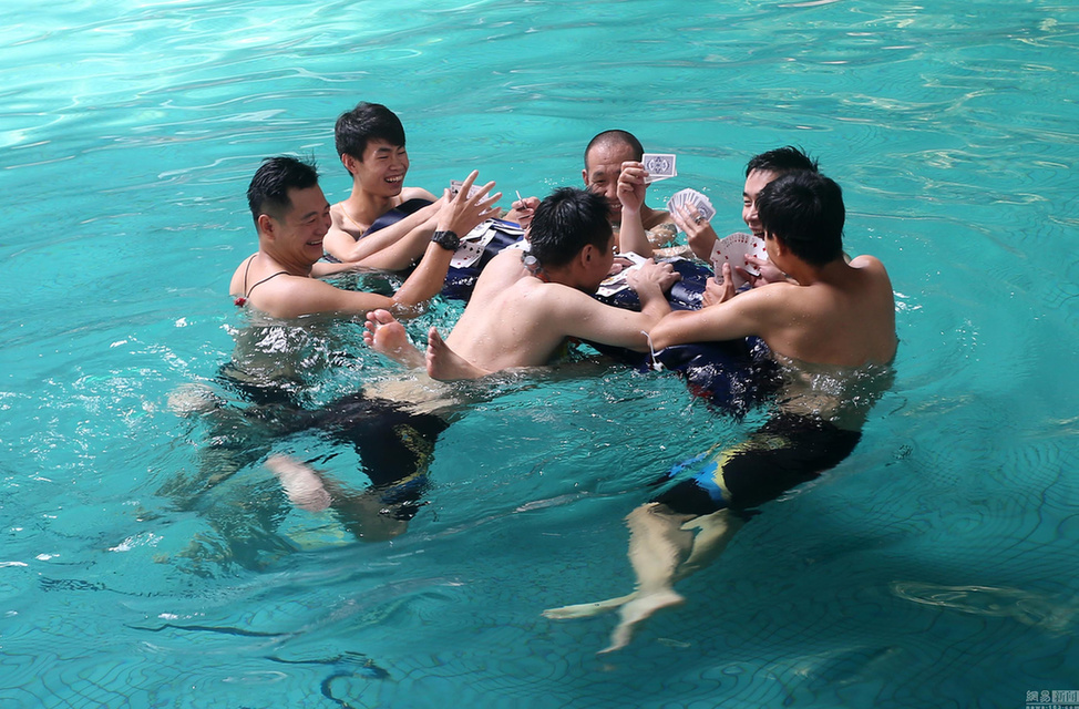 山东潍坊现高温天气 市民水中打牌抗酷暑