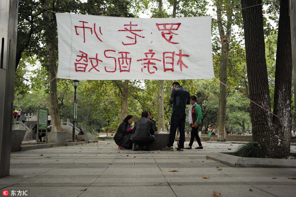 武汉解放公园“相亲角”渐成产业 父母“打伞招亲”煞费苦心