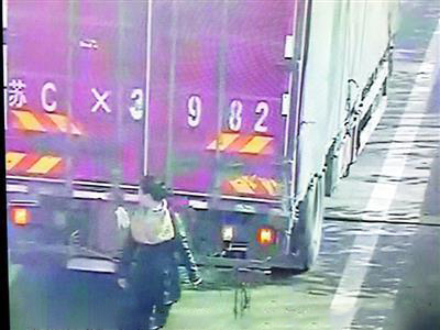 货车高速上违规倒车 女子用身体遮车牌躲监控