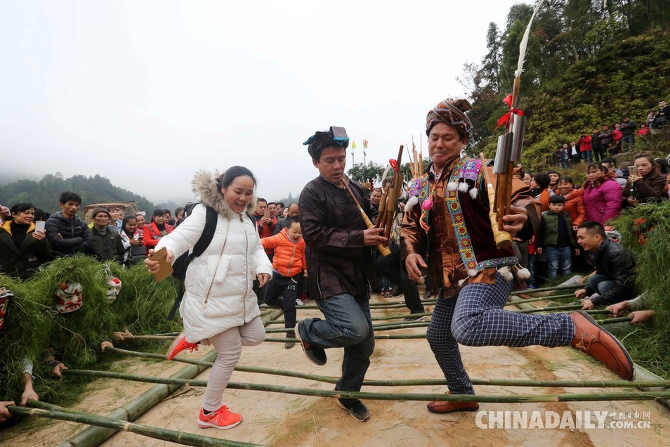 2月5日,在广西融安县长安镇安宁村大袍屯,游客与苗族群众共跳竹竿舞.