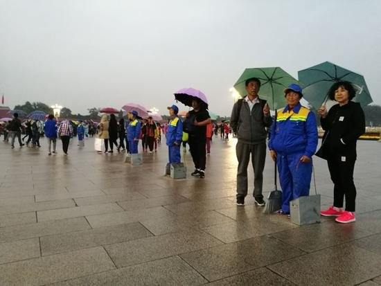 天安门广场下雨 游客自发为环卫工打伞