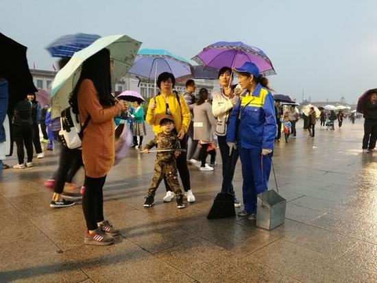 天安门广场下雨 游客自发为环卫工打伞