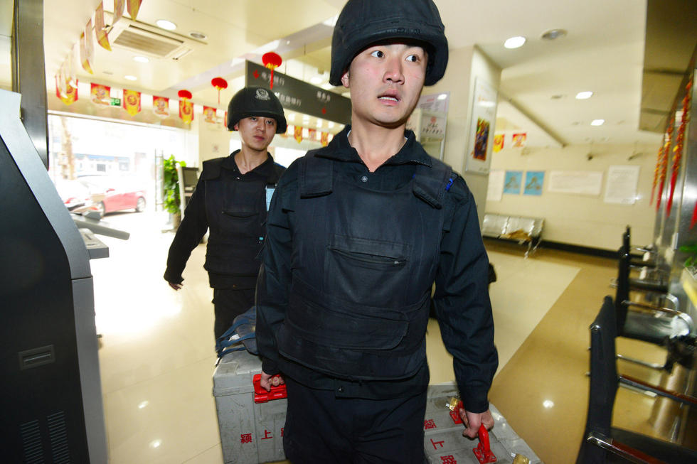 2016年3月30日,安徽阜阳市,在押运员的护送下,交接员将款箱安全送入